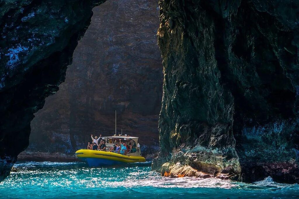 Boat Trip Through Sea Caves — unique travel destinations in the USA Boat navigating through sea caves with towering cliffs in the background. — unique travel destinations in the USA