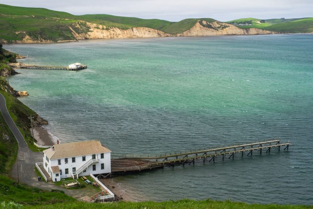 Bodega Bay Scenic View — road trip USA ideas Scenic view of Bodega Bay with a pier and green hills in the background — road trip USA ideas