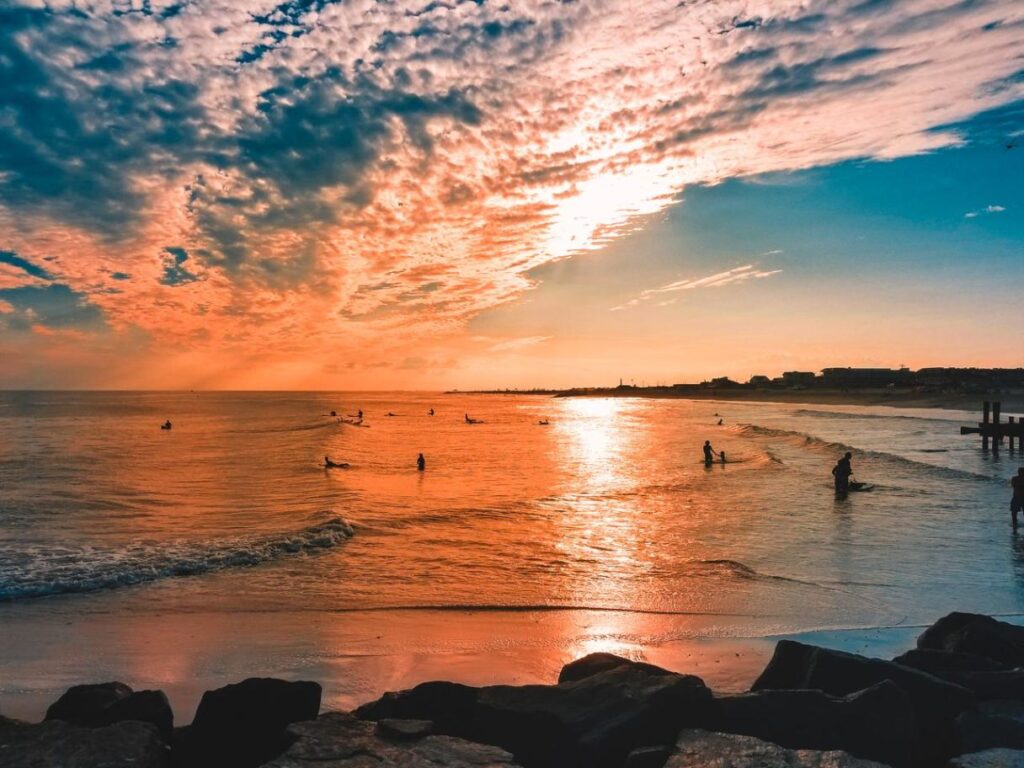 Charming Beach Sunset — charming small towns in the USA Sunset over a beach with surfers and people enjoying the water. — charming small towns in the USA