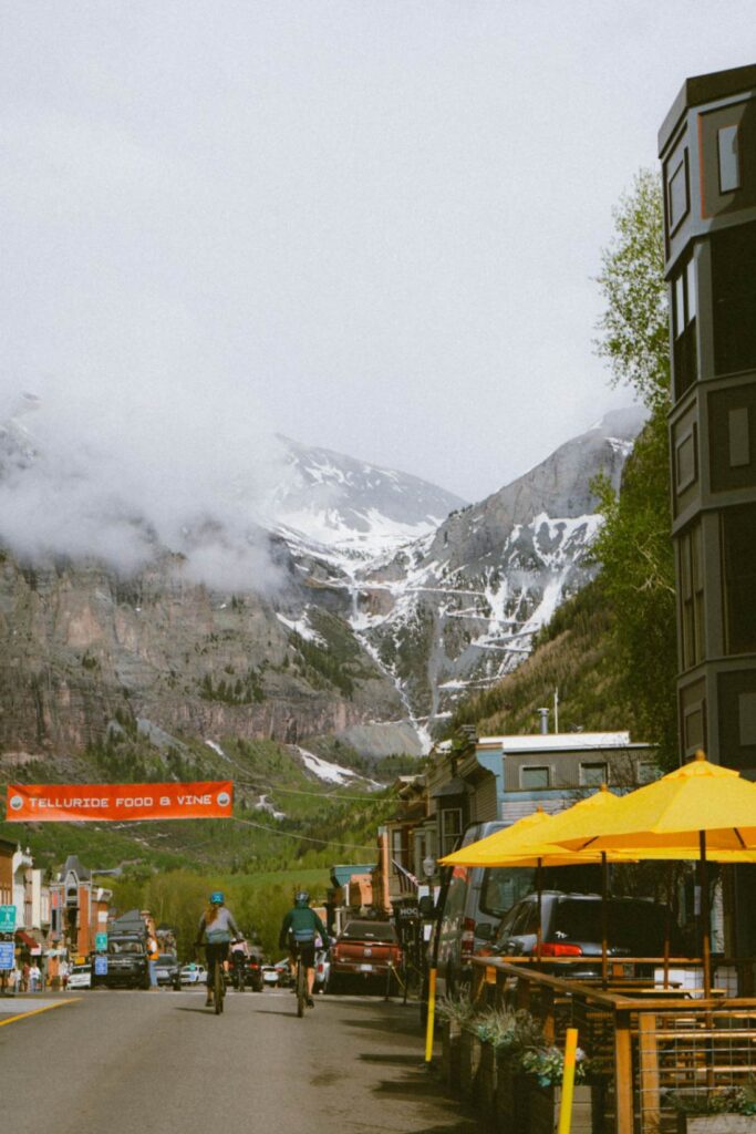 Charming Small Town in Telluride — charming small towns in the USA Bicyclists riding through a charming small town with mountains in the background. — charming small towns in the USA
