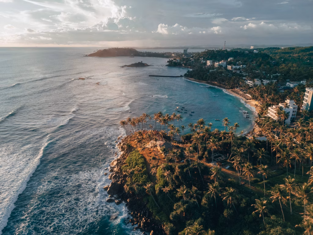 Coastal Beauty of Sri Lanka — underrated countries to visit Aerial view of a coastal area in Sri Lanka with palm trees and waves. — underrated countries to visit