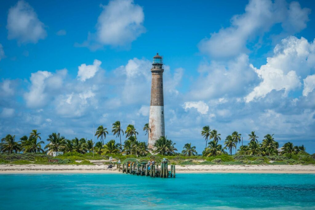 Dry Tortugas National Park Lighthouse — secret places in the USA Dry Tortugas National Park lighthouse surrounded by clear blue water and palm trees. — secret places in the USA