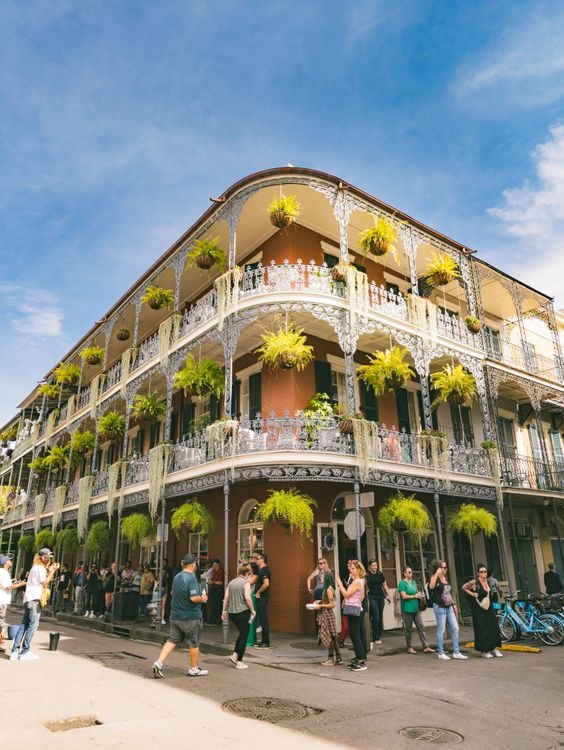 Historic New Orleans Architecture — cheap places to travel in USA Historic building in New Orleans with hanging plants and people walking by. — cheap places to travel in USA
