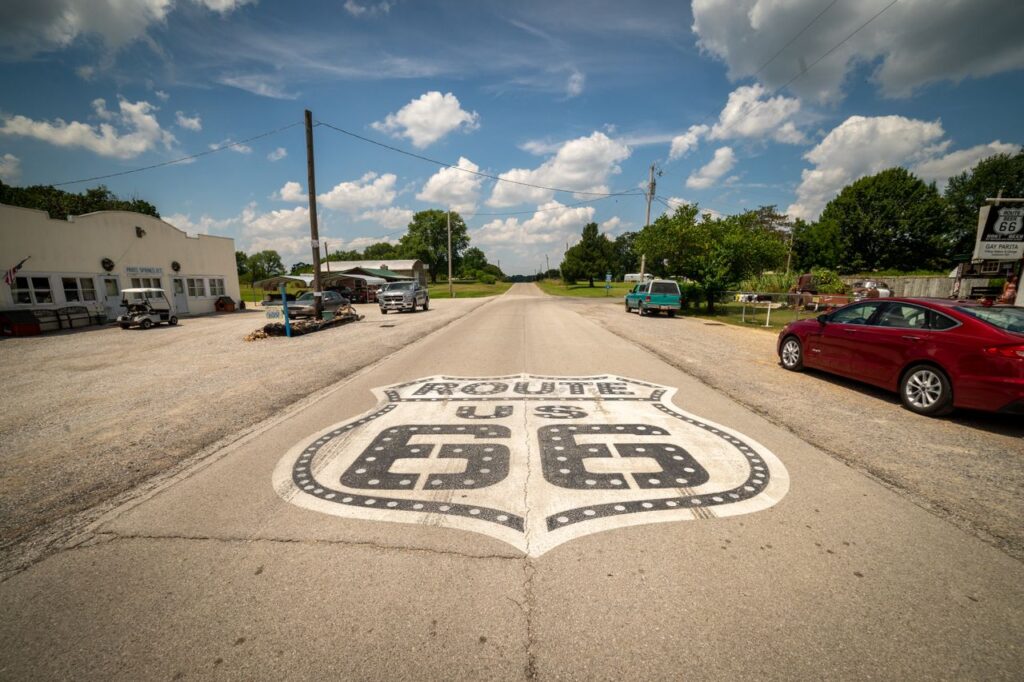 Historic Route 66 Sign — RV USA road trip routes Historic Route 66 road sign on pavement with blue sky and clouds — RV USA road trip routes
