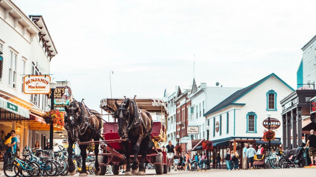 Horse-Drawn Carriage in Small Town — charming small towns in the USA Horse-drawn carriage in a charming small town with shops and people walking. — charming small towns in the USA