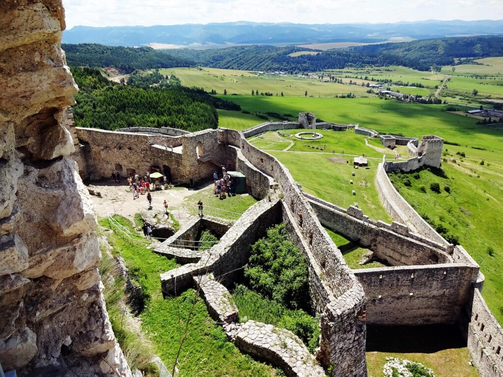 Spiš Castle Overview — places to visit in Slovakia Spiš Castle ruins with expansive green landscape in the background. — places to visit in Slovakia