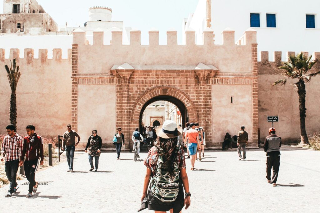 Exploring a Historic City Gate — easier vacation planning tips A traveler exploring a historic city gate with palm trees and people walking around. — easier vacation planning tips