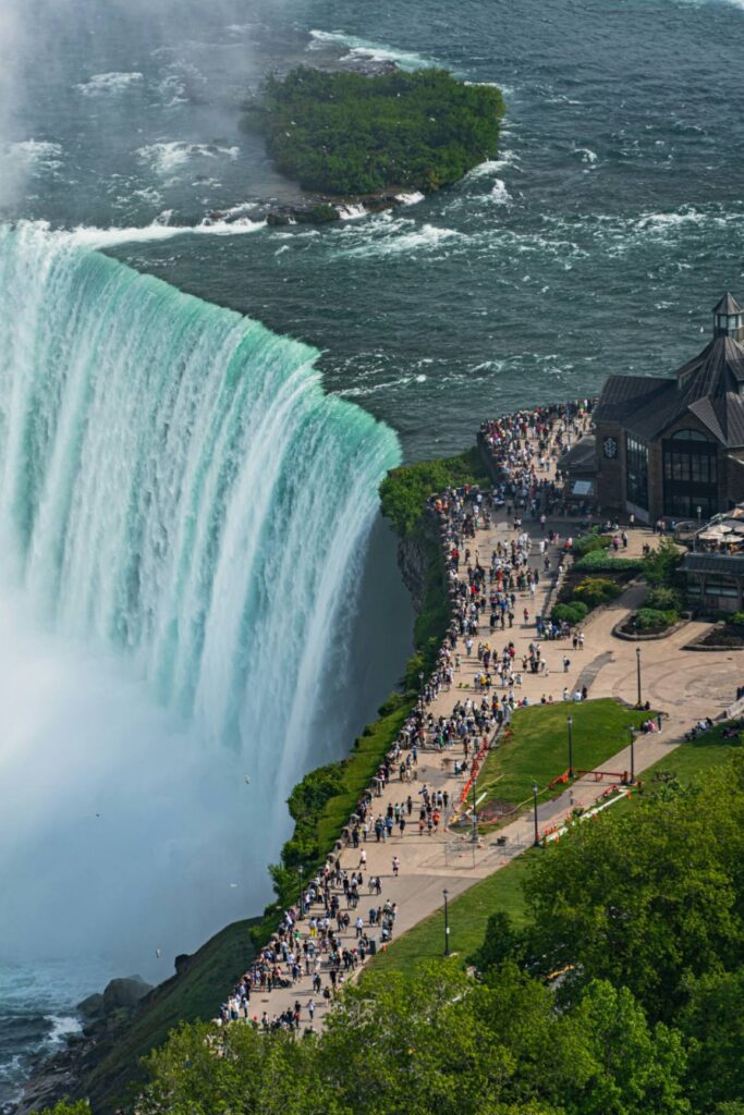 Niagara Falls Viewpoint — beautiful places in America to visit Niagara Falls cascading into the river with visitors along the viewing area. — beautiful places in America to visit