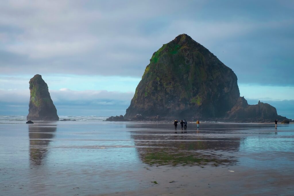Oregon Coast Landscape — Places to Visit in the Western USA Oregon Coast with Haystack Rock and beachgoers — Places to Visit in the Western USA