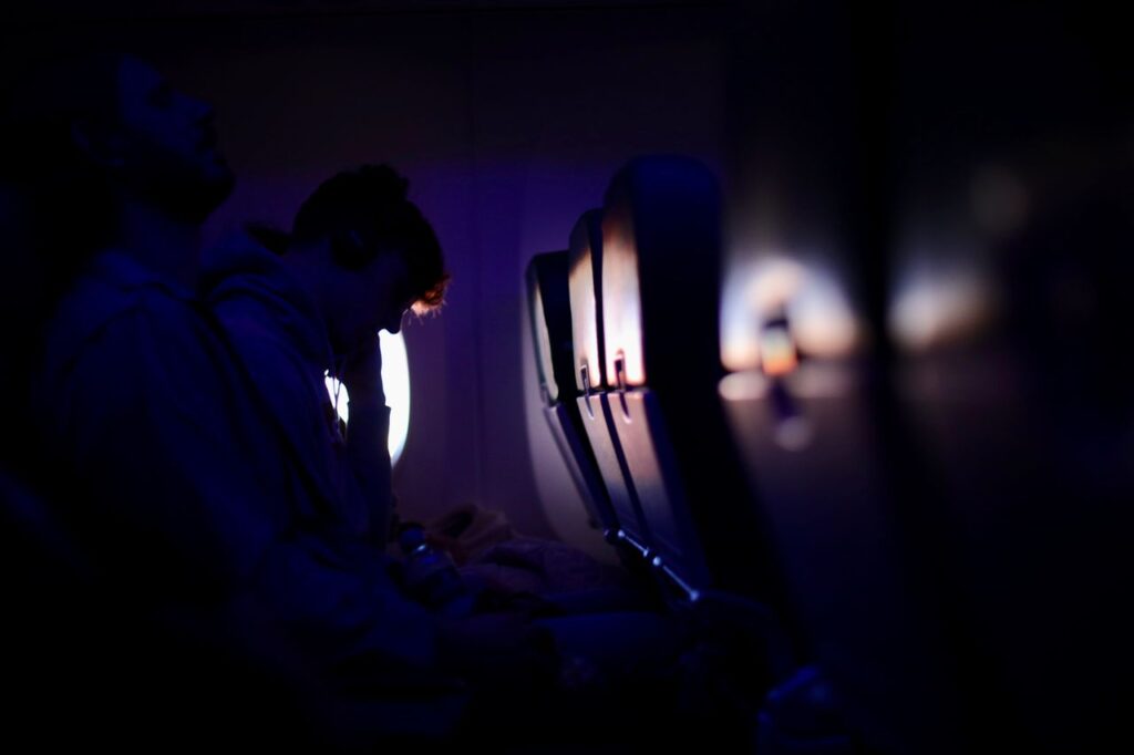 Comfort on Long Flights — long flight comfort essentials Passengers on a plane during a long flight in low light — long flight comfort essentials