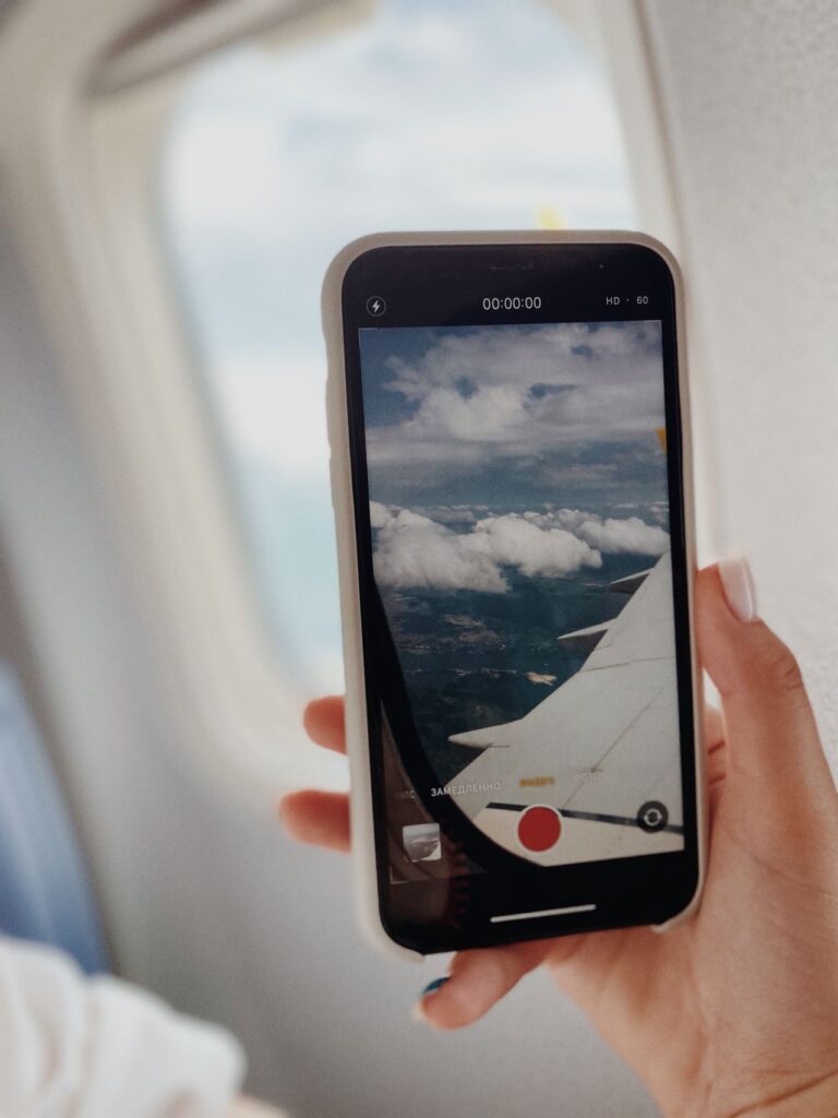 Capturing Travel Moments — international travel tips for first-time A smartphone capturing clouds and airplane wing during a flight. — international travel tips for first-time