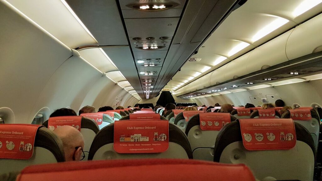 Airplane Cabin Interior — long flight comfort essentials Interior view of an airplane cabin showing passenger seats and overhead lighting. — long flight comfort essentials