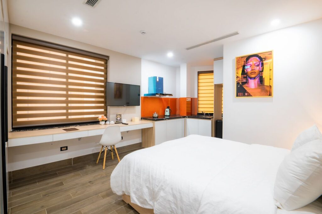 Comfortable Hotel Room for Solo Travelers — Solo Travel Safety Tips Modern hotel room with a bed, desk, and kitchenette. — Solo Travel Safety Tips