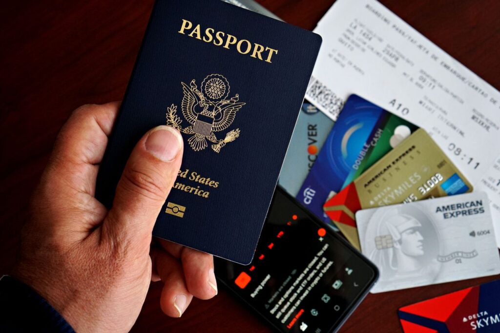 Travel Documents for First-Time Travelers — international travel tips for first-time A hand holding a U.S. passport with travel documents and credit cards on a table. — international travel tips for first-time