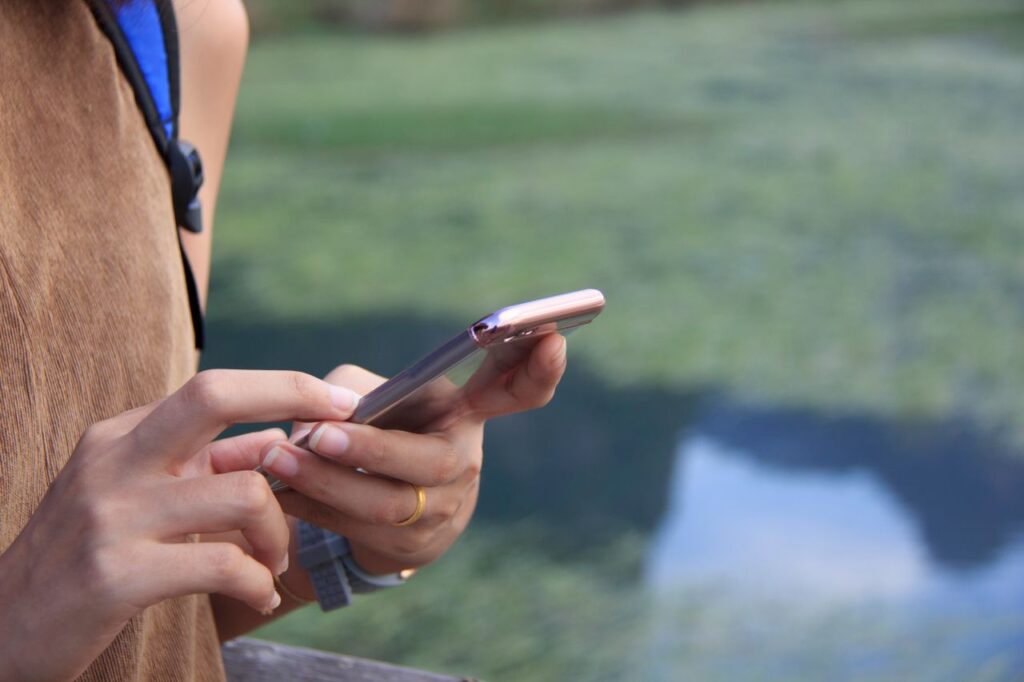 Using Smartphone While Traveling — international travel tips for first-time Person using smartphone near water while traveling — international travel tips for first-time