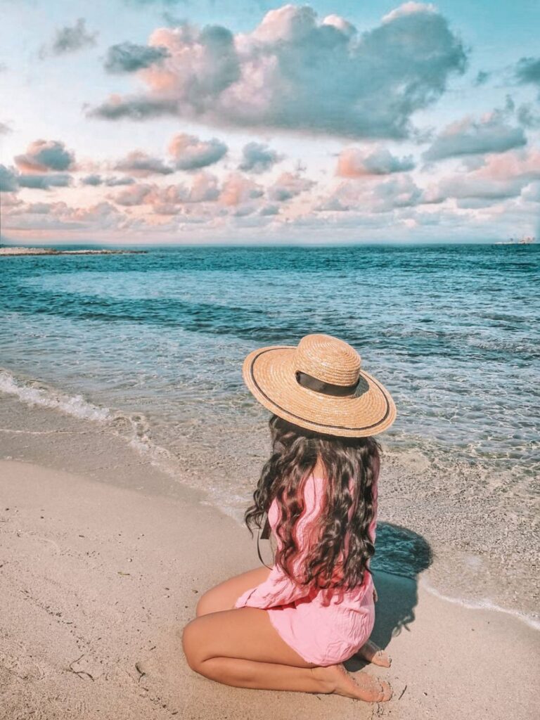 Beach Relaxation for Solo Female Travelers — 8 solo female travel ideas Woman sitting on the beach looking at the ocean — 8 solo female travel ideas