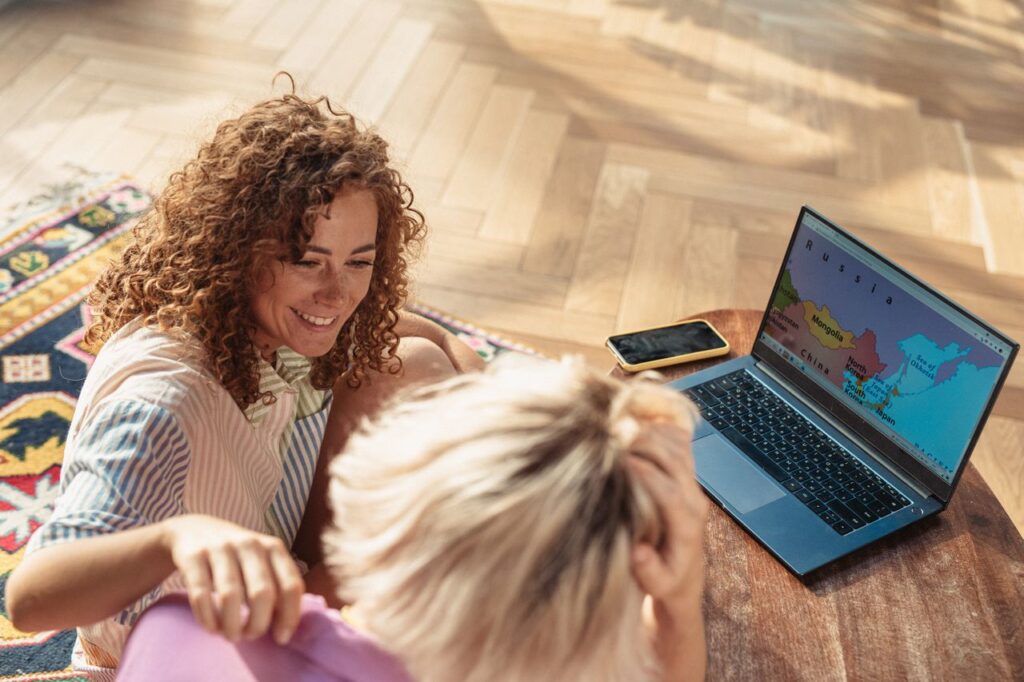 Travel Planning Together — easier vacation planning tips Two people planning a trip using a laptop on the floor. — easier vacation planning tips