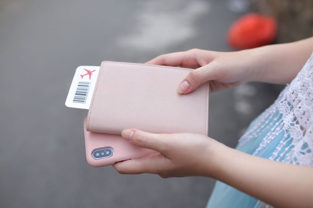 Travel Essentials for Vacation Travel essentials including a passport wallet and phone with boarding pass.