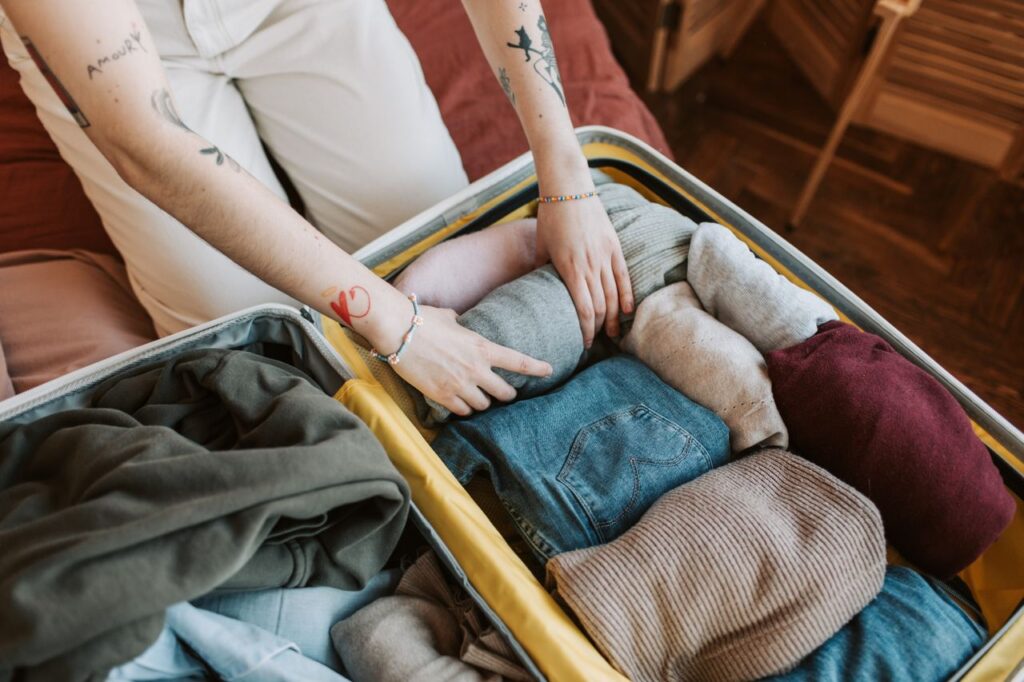 Packing a Carry-On Suitcase — carry-on packing essentials A person packing a suitcase with neatly folded clothing for travel. — carry-on packing essentials