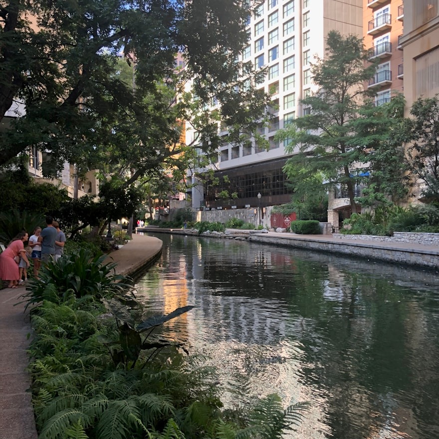 River Walk Scenic View — cheap places to travel in USA Scenic view of the River Walk with greenery and buildings in the background. — cheap places to travel in USA