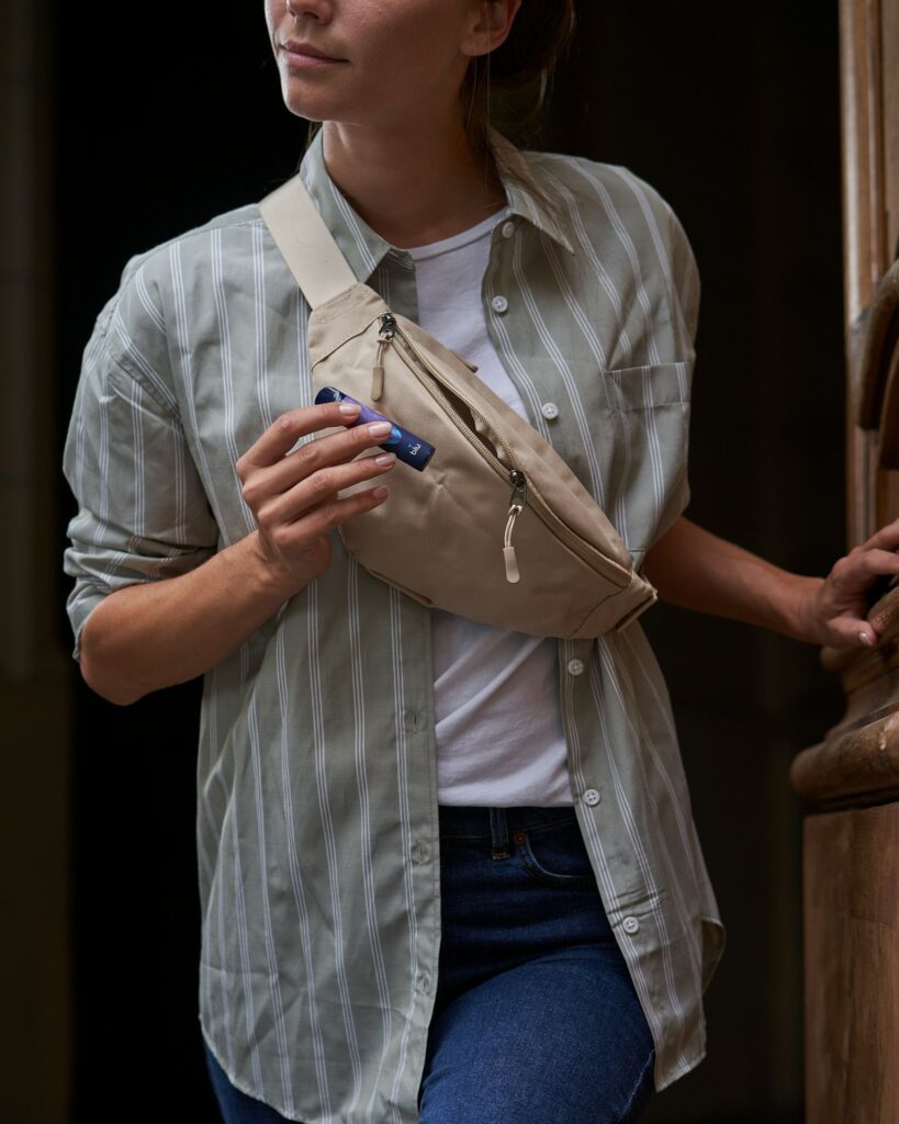 Versatile Personal Bag for Travel — travel essentials for women A woman wearing a striped shirt and holding a personal bag. — travel essentials for women