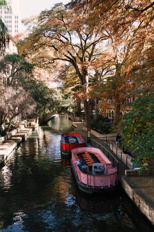 San Antonio River Walk — cheap places to travel in USA San Antonio River Walk with boats and autumn trees — cheap places to travel in USA