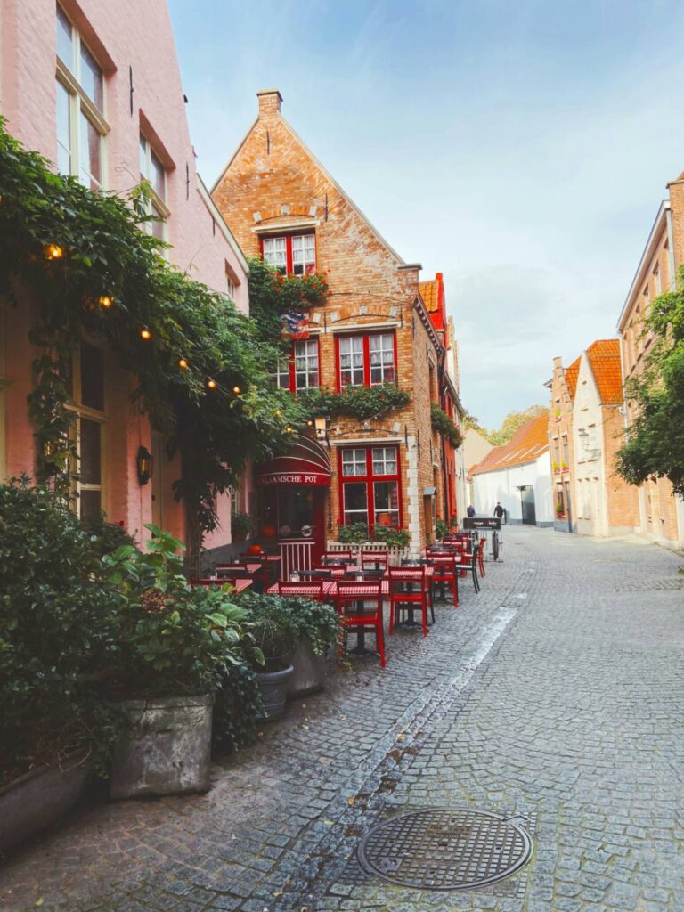 Charming Bruges Street — beautiful getaways in Europe Charming street in Bruges, Belgium with red tables and historic buildings. — beautiful getaways in Europe