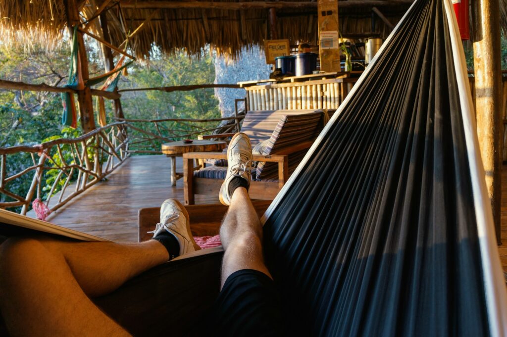 Affordable Accommodation Relaxation — Budget Travel Tips Person relaxing in a hammock at an affordable accommodation — Budget Travel Tips