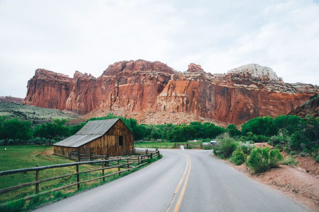 Utah Road Trip Scenery — RV USA road trip routes Scenic view along a road in Utah with red rock formations and a wooden barn. — RV USA road trip routes