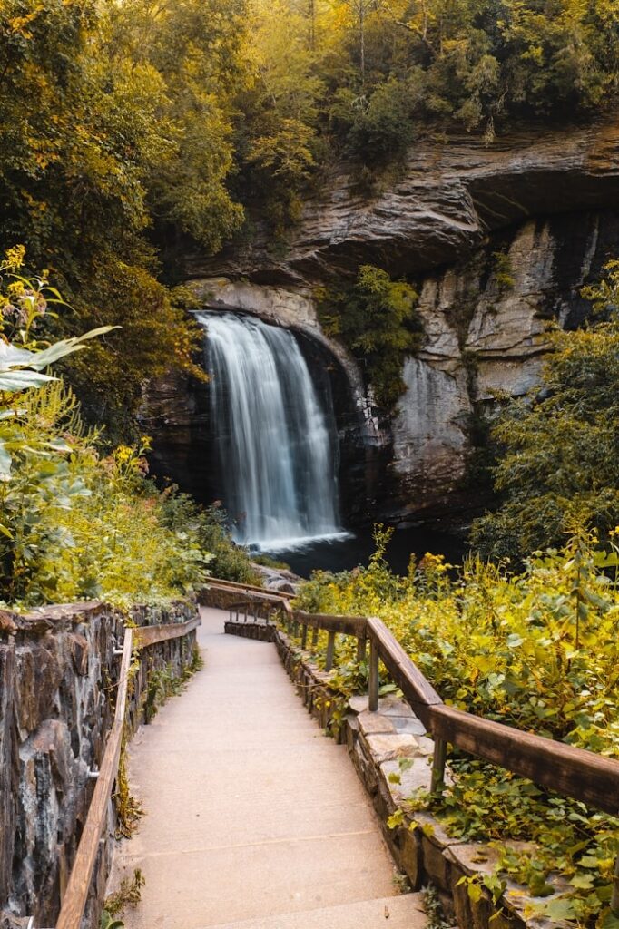 Waterfall on the Blue Ridge Parkway — road trip USA ideas Waterfall surrounded by lush greenery and a stone pathway — road trip USA ideas
