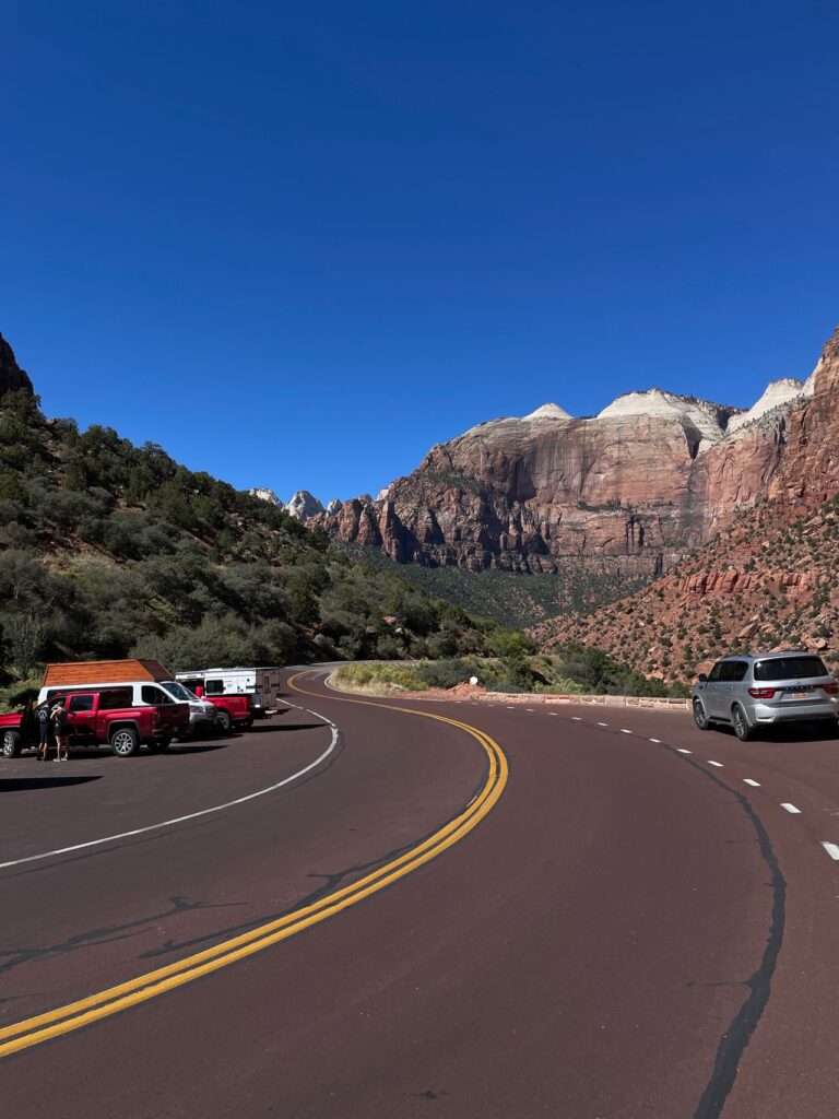 Winding Road in Zion National Park — USA cross-country road trip Scenic view of a winding road in Zion National Park with parked vehicles. — USA cross-country road trip