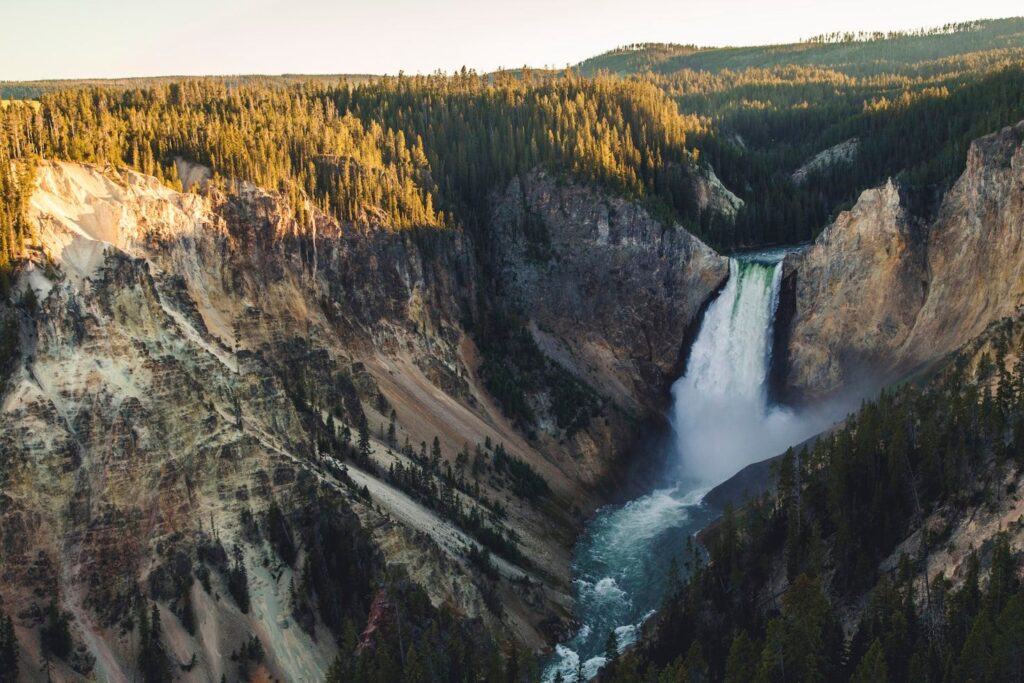 Yellowstone National Park Waterfall — Places to Visit in the Western USA Yellowstone National Park waterfall surrounded by cliffs and forests — Places to Visit in the Western USA