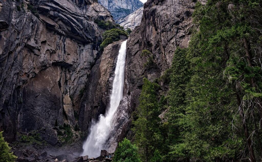 Yosemite Falls in Yosemite National Park — beautiful places in America to visit Yosemite Falls cascading down granite cliffs surrounded by lush greenery. — beautiful places in America to visit